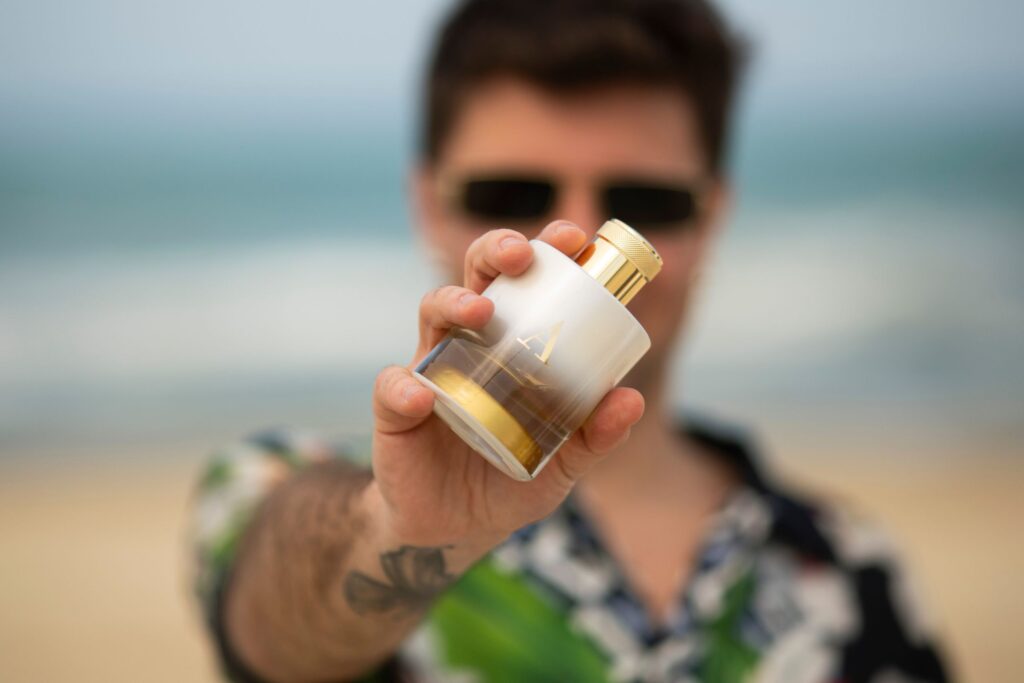 Profumi da Riviera 5 profumi per un'estate al tramonto, al mare uomo che mostra flacone bianco e oro