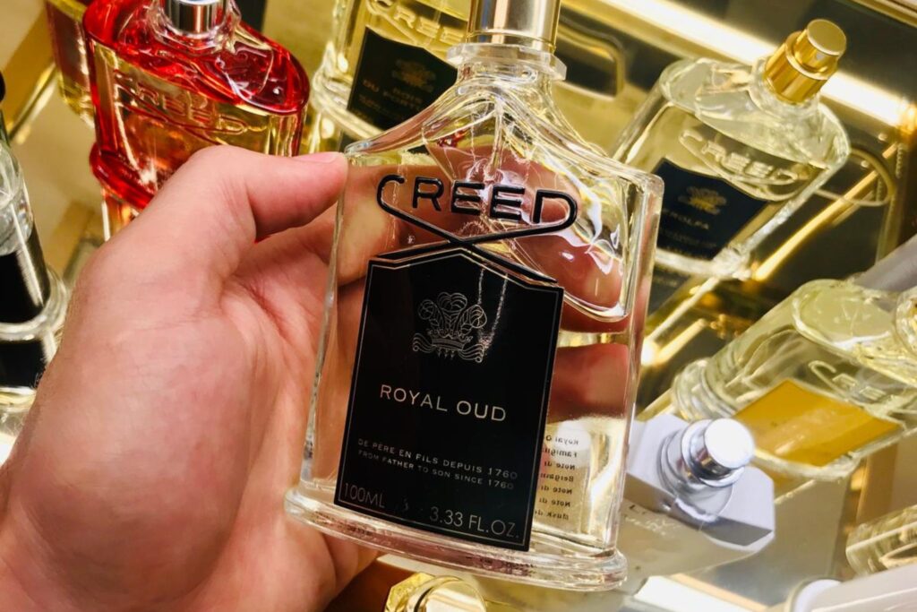 flacone profumo creed royal oud nero uomo in mano in negozio profumi