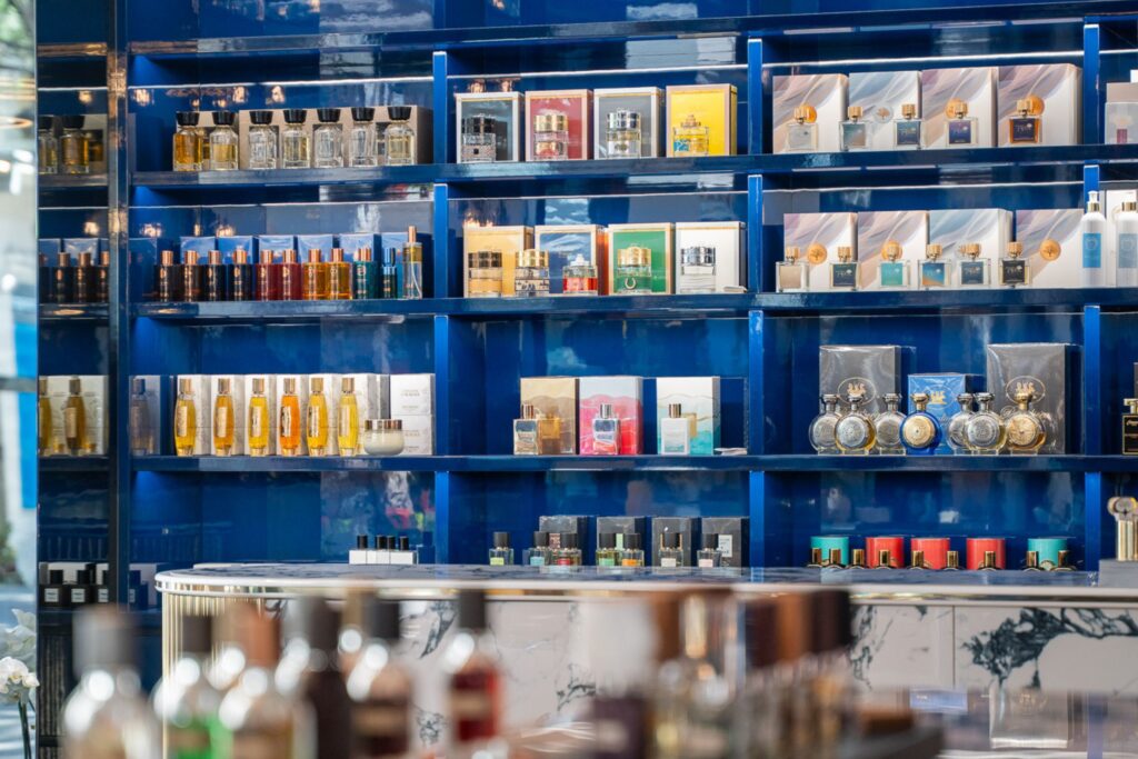 Profumi al sandalo: scaffali blu con flaconi colorati di profumi. quali scegliere e quali sono i migliori? Ecco le fragranze al sandalo più amate del momento.