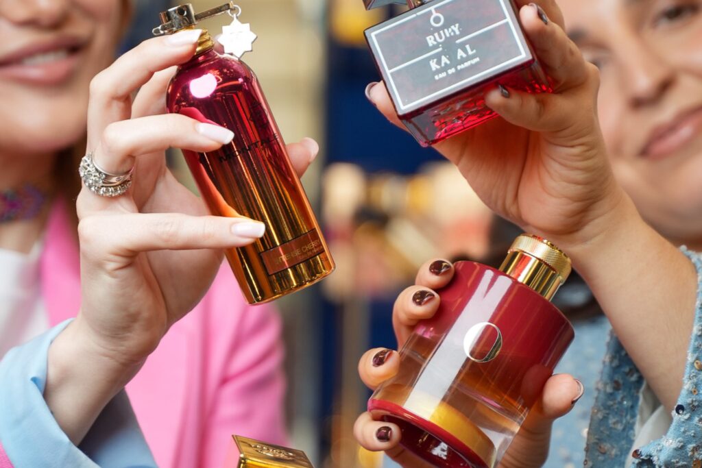 profumi alla ciliegia, mani tengono flaconi profumi, flaconi rossi profumi, boccetta con o. Profumi alla ciliegia: come scegliere i migliori profumi di nicchia con questa nota. Ecco la scelta di Riviera Profumi.