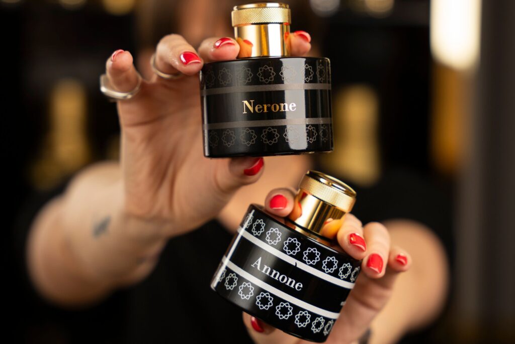 mani con smalto rosso tengono due flaconi neri di profumo Quali sono i migliori profumi oud per iniziare? Ecco la guida dove vi spieghiamo di più su questa nota affascinante delle maison profumiere.